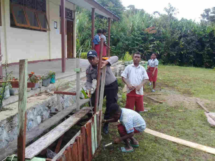 Caption : Terlihat Kanit Binmas Polsek Waris, saat mengajari pelajar SD menanam bunga dan pohon di lingkungan sekolah SD YPPK Epinos