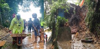 Caption : Terlihat anggota polri bersama warga saat membantu membersihkan longsor yang menutupi badan jalan dan rumah milik Hendrik Lewakabesi di Polimak III Pintu Angin, Selasa (229/03/2019) pagi.