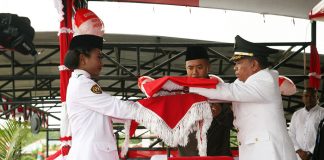 Bupati Keerom Muh. Markum saat menyerahkan bendera Merah Putih kepada petugas pengibar bendera dalam upacara HUT Kemerdekaan Republik Indonesia ke 74 Tahun di Kabupaten Keerom.