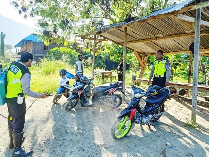 Personel Sat Lantas Polres Jayapura saat melakukan penyemprotan cairan disinfektan untuk memutus mata rantai penyebaran Covid-19 di pangkalan ojek Waibu, Sentani Barat, Kabupaten Jayapura, Jumat (29/5/20)