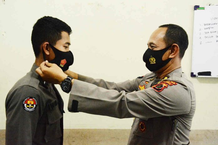 Caption : Kabid Humas Polda Papua Kombes Pol. Drs. Ahmad Musthofa Kamal, SH saat mengenakan Masker kepada salah satu anggota Polda Papua