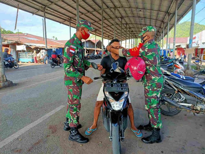 Caption : Prajurit Kodim 1709/Yawa saat membagikan masker di sepanjang jalan-jalan protokol Kota Serui Kabupaten Kepulauan Yapen, pada Senin (19/10/2020).