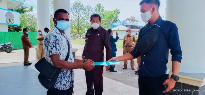 Ketua HMPJ, Alber Kalolik sedang menyerahkan program kerja kepada ajudannya Bapak Bupati Jhon Richard Banua dan bapak bupati berdiri di tengah sedang menyaksikan penyerahan program kerja tersebut di depan gedung DPRD kabupaten Jayawijaya Senin, (28/12/2020)