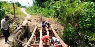 Caption : TNI-Polri bersama warga saat membangun jembatan untuk menghubungkan jalan antar Kampung di Distrik Raimbawi, Kabupaten Kepupauan Yapen, Minggu (31/01/2021).