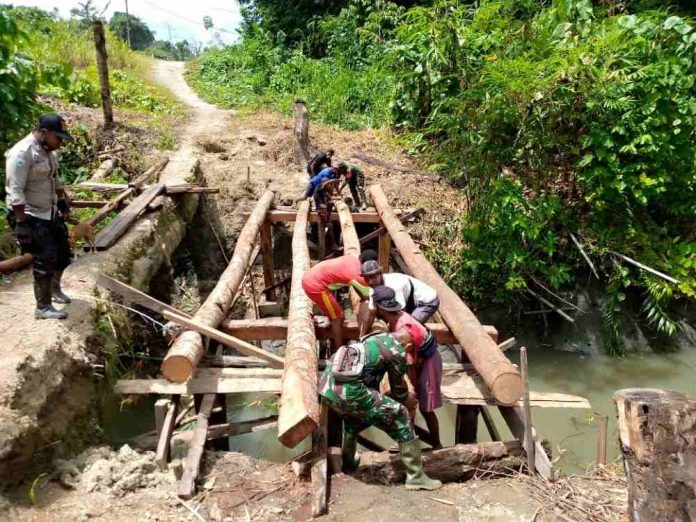 Caption : TNI-Polri bersama warga saat membangun jembatan untuk menghubungkan jalan antar Kampung di Distrik Raimbawi, Kabupaten Kepupauan Yapen, Minggu (31/01/2021).