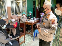 Dir Reskrimsus Polda Papua, Kombes Pol. Ricko Taruna Mauruh, S.IK., bersama Ketua PWNU Provinsi Papua Dr.H. Toni Wanggai saat berbincang-bincang dengan warga yang mengikuti vaksinasi Covid-19 di Halaman SMP Nurul Huda, Kota Jayapura