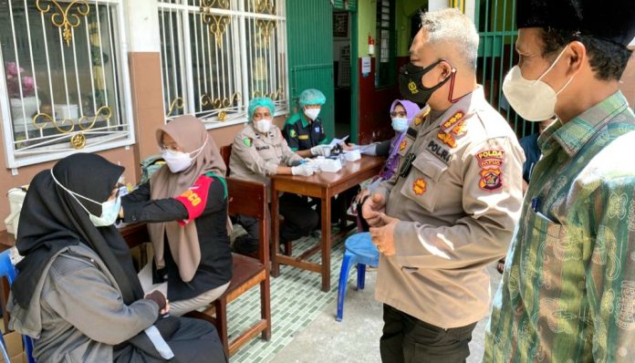 Dir Reskrimsus Polda Papua, Kombes Pol. Ricko Taruna Mauruh, S.IK., bersama Ketua PWNU Provinsi Papua Dr.H. Toni Wanggai saat berbincang-bincang dengan warga yang mengikuti vaksinasi Covid-19 di Halaman SMP Nurul Huda, Kota Jayapura