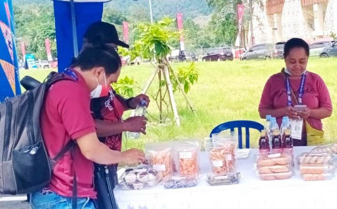 Mama Tini saat melayani pembeli yang akan membeli dagangannya di venue menembak, Kampung Harapan Mama Tini saat melayani pembeli yang akan membeli dagangannya di venue menembak, Kampung Harapan