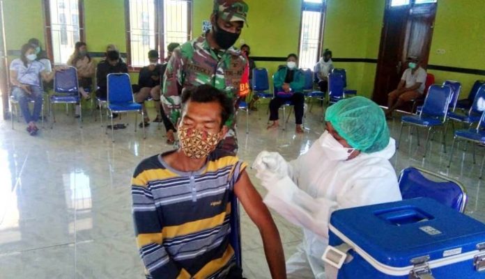 Babinsa Koramil 02/Tigi Kodim 1703/Deiyai Sertu Patrisius saat melihat pelaksanaan vaksinasi Covid-19 di Aula Kantor Dinas Kesehatan, Distrik Tigi, Kabupaten Deiyai, Selasa ( 05/10/2021 )
