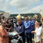 Asisten I Bidang Pemerintahan dan Hukum Setda Provinsi Papua, Doren Wakerkwa saat menyerahkan SK Kodefikasi 14 Kampung Adat kepada Bupati Jayapura, Mathius Awoitauw, Jumat (19/8/2022).