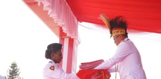 Caption : PJ Puncak Jaya, Tumiran, S.Sos, M.AP saat menyerahkan bendera kepada petugas Bendera pada upacara peringatan HUT RI ke-79 di lapangan Alun-alun Kota Baru, Mulia Kabupaten Puncak Jaya, Sabtu (17/08/2024).