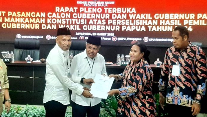 Ketua KPU Papua, Diana Dorthea Simbiak saat menyerahkan SK Penetapan Nomor Urut kepada Paslon yang mengalami perubahan komposisi dari BTM-YB menjadi BTM-CK