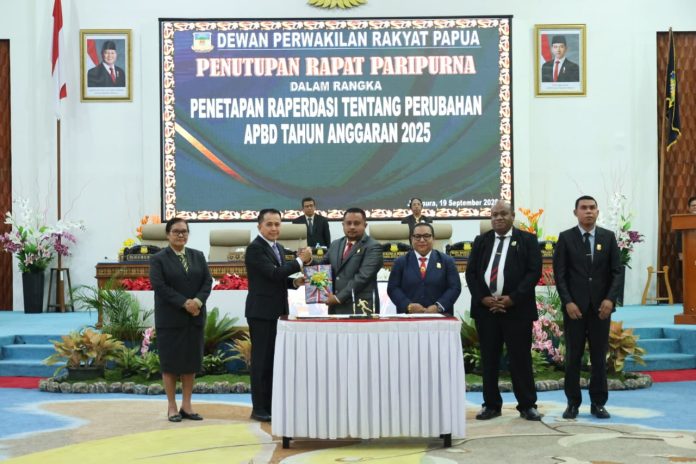 Caption : Ketua DPR Papua, Denny Henrry Bonai, ST. MM saat menyerahkan persetujuan APBD Perubahan 2025, kepada Penjabat Gubernur Papua, Agus fatoni di ruang siang sidang paripurna DPR Papua, Jumat (19/9/2025) malam.