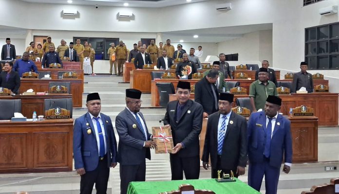 Ketua DPRK Jayapura, Ruddy Bukanaung saat menyerahkan Perda Perubahan APBD Tahun 2025 yang baru disahkan kepada Bupati Jayapura, Dr. Yunus Wonda,SH,MH.