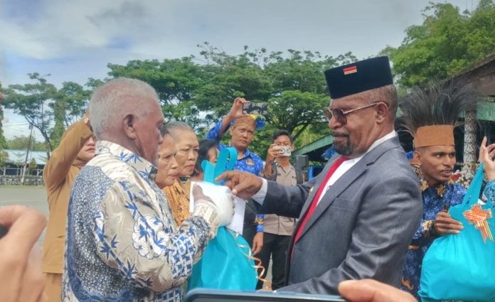 Bupati Jayapura, Yunus Wonda saat menyerahkan banuan sosial kepada penerima manfaat pada momen Peringatan Hari Pahlawan 10 November 2025 di Lapangan Upacara Kantor Bupati Jayapura, Gunung Merah Sentani