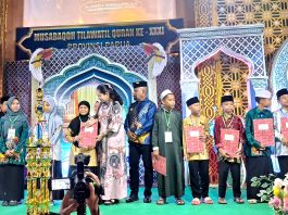 Bupati Jayapura Dr. Yunus Wonda, S.H., M.H. bersama Ibu saat menyerahkan sertifikat kepada peserta MTQ ke-31 yang berhasil meraih predikat terbaik